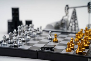 OPEC kelimesi. Parçalı bir satranç tahtası, yağ varilleri ve arka planda bir yağ pompası krikosu.