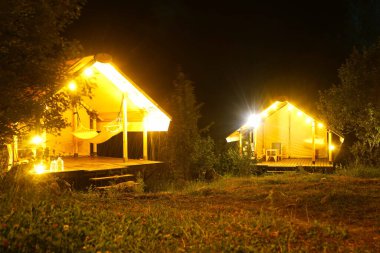 Glamping. Dağlık bir alanda hamaklı bir çardak. Çoklu ampullerle gece vakti.
