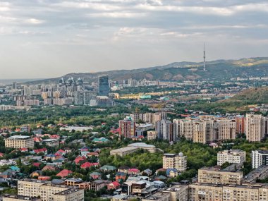 Almaty, Kazakistan - 08.12.2025: Şehrin üst kesimlerinde çeşitli konut binaları. Dağ manzarası. İnsansız hava aracının görüntüsü. Yaz akşamındayız..