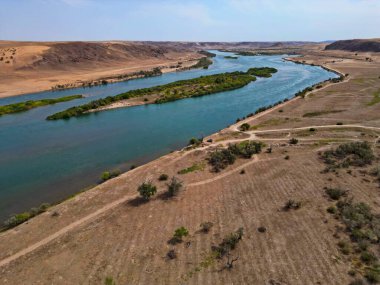 Ili Nehri ve kumlu kıyı bölgesi. Semirechye 'deki en büyük nehir. İnsansız hava aracının görüntüsü. Yılın yaz zamanı..