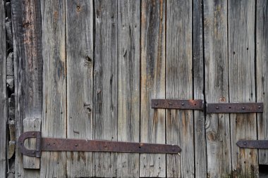 An iron bracket on an old wooden garage and barn door.