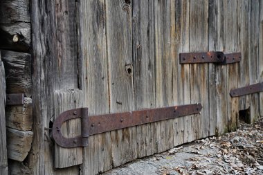 An iron bracket on an old wooden garage and barn door.