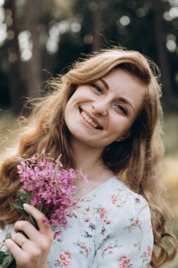 Tarla çiçekli genç kız ışıl ışıl gülümsüyor