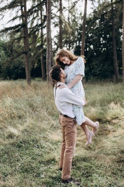 Genç ve mutlu bir çift. Bir adam güzel bir doğayla bir kızı kollarına alır.