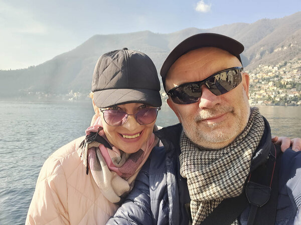 Selfie on the shores of Lake Como. Happy married couple of mature age. Italy, end of February
