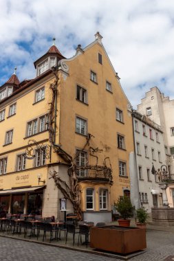 LINDAU, GERMANY - 2 Nisan 2023: Almanya 'da Bodensee Gölü' ndeki Bavyera şehri Lindau 'da rahat bir cadde. Kafesi olan geleneksel yaşlı Alman evleri..