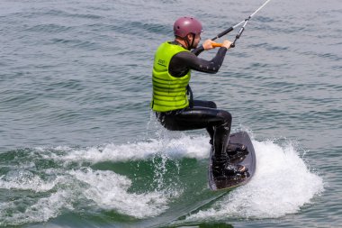 ROMANSHORN, SWitzERLAND - 4 Haziran 2023: bir kılavuz mekanizması ile Wakeboard. Bilinmeyen bir adam kabloyu tutuyor ve su kayağı yapmaya başlıyor.