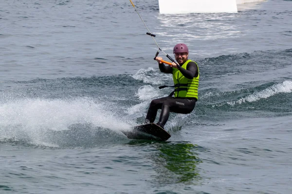 stock image ROMANSHORN, SWITZERLAND - JUNE 4, 2023: Wakeboarding with a guide mechanism. An unknown athlete holds on to the cable, performing tricks in the direction of travel.