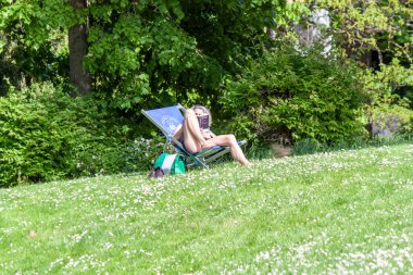FREIBURG, ALMANY - 6 MAYIS 2023 Tanımlanamayan bir kadın, güneşlenme odasında kitap okuyor.