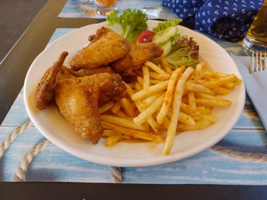 Kızarmış tavuk kanadı ve sebzeli patates kızartması.