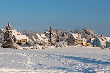 Avrupa 'nın bir köyünde güzel bir kış. Kır evlerinin arka planında karla kaplı bir tarlanın manzarası. Almanya