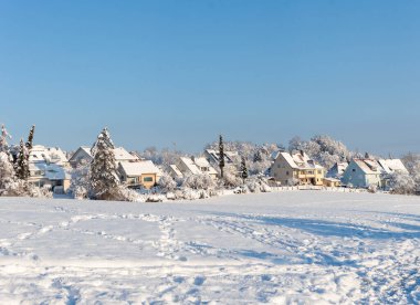 Avrupa 'nın bir köyünde güzel bir kış. Kır evlerinin arka planında karla kaplı bir tarlanın manzarası. Almanya