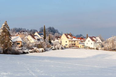 Avrupa 'nın bir köyünde güzel bir kış. Kır evlerinin arka planında karla kaplı bir tarlanın manzarası. Almanya