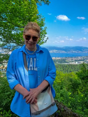 Kafe masasında elinde bir fincan kahveyle çekici, olgun bir kadın. Baharın başlangıcı