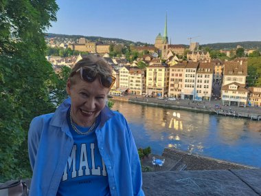 Kafe masasında elinde bir fincan kahveyle çekici, olgun bir kadın. Baharın başlangıcı