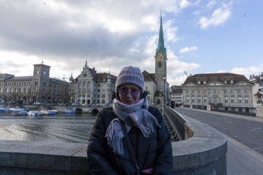 Kafe masasında elinde bir fincan kahveyle çekici, olgun bir kadın. Baharın başlangıcı