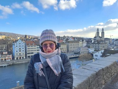 Kafe masasında elinde bir fincan kahveyle çekici, olgun bir kadın. Baharın başlangıcı