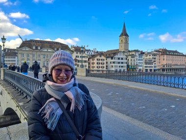 Kafe masasında elinde bir fincan kahveyle çekici, olgun bir kadın. Baharın başlangıcı