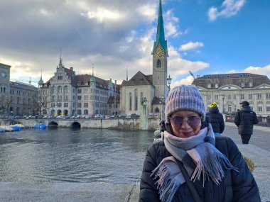 Kafe masasında elinde bir fincan kahveyle çekici, olgun bir kadın. Baharın başlangıcı