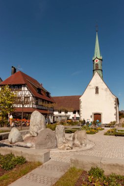 UNTERUHLDINGEN, GERMANY - 27 Nisan 2024: Unteruhldingen 'deki Bodensee seti üzerindeki kilise ve taş anıt