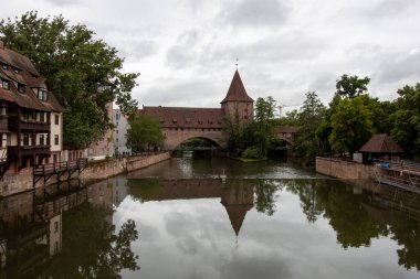 NUREMBERG, GERMANY - 18 Mayıs 2024: Schlayerturm Ortaçağ Kulesi ve Pegnitz Nehri üzerindeki Kettensteg Köprüsü