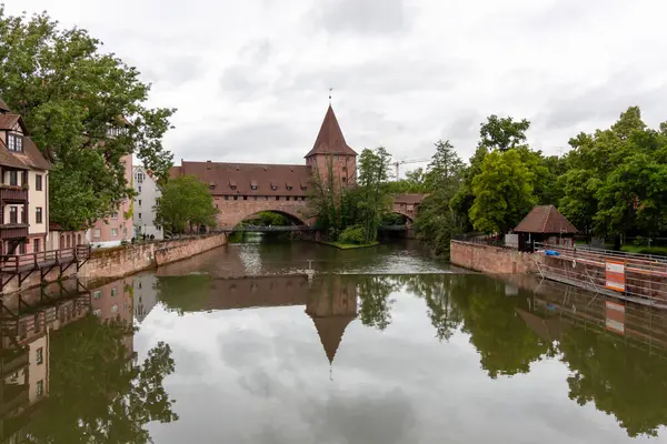 stock image NUREMBERG, GERMANY - MAY 18, 2024: Schlayerturm medieval tower and Kettensteg (Chain Bridge) over river Pegnitz