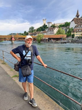 İsviçre 'nin Lucerne şehrindeki Reuss nehrinin setinde kameralı olgun bir adam.
