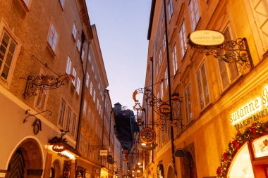 SALZBURG, AUSTRIA - 3 Şubat 2024: Ünlü tarihi Getreidegasse sokağı birden fazla reklam levhası ile. Salzburg 'un eski kenti 1997 yılında UNESCO Dünya Mirası listesine alındı.