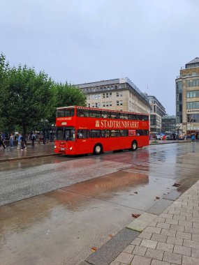 HAMBURG, GERMANY - AUGUST 14, 2024: Red hop on hop off sightseeing bus in Rathausmarkt square clipart