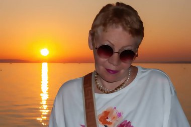 Olgun bir kadının portresi güzel bir yaz günbatımının arka planında Langenargen 'deki Constance Gölü' nün setinde.