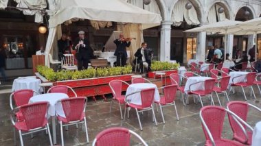Venedik, İtalya - 24 Ekim 2024: St. Mark Meydanı 'ndaki Grancafe Quadri terasındaki müzisyenler dünyaca ünlü Bella Ciao' yu sahneledi.