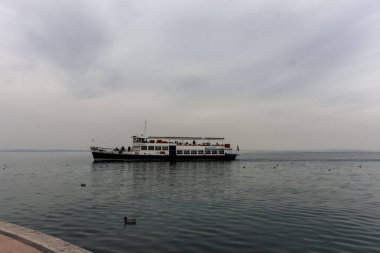 LAZISE, İtalya - 25 Ekim 2024: Küçük gemi S. Martino bulutlu bir Ekim günü Lazise limanına varır.