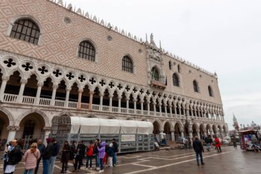 Venedik, İtalya - 24 Ekim 2024: Venedik, İtalya 'daki Derebeyi Sarayı (Palazzo Ducale), süslemeleri ve kemerli sütunları olan tarihi bir simgedir. Turistler sarayın önündeki meydanda toplandılar.