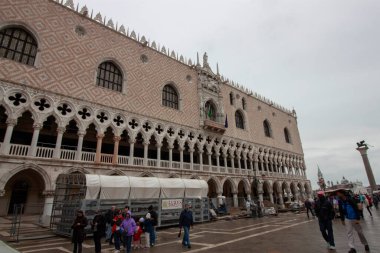 Venedik, İtalya - 24 Ekim 2024: Venedik, İtalya 'daki Derebeyi Sarayı (Palazzo Ducale), süslemeleri ve kemerli sütunları olan tarihi bir simgedir. Turistler sarayın önündeki meydanda toplandılar.