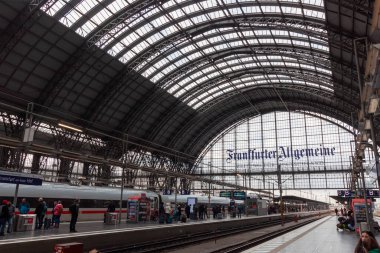 FRANKFURT (MAIN), GERMANY - 4 Aralık 2024: Frankfurt Hauptbahnhof (Frankfurt Merkez İstasyonu), Almanya, platformunda bir tren ve bekleyen insanlar. Ayırt edici cam ve çelik çatı görünür.