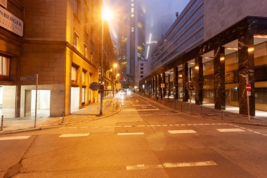 FRANKFURT (MAIN), GERMANY - DECEMBER 1, 2024: A street in Frankfurt's financial district (Bankenviertel) at dusk or evening, with illuminated skyscrapers and a 