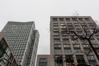 Almanya 'nın finans bölgesi Frankfurt am Main' deki (Bankenviertel) ofis binalarının manzarası, gri, bulutlu bir gökyüzü altında mimari tarzlarda bir karşıtlık sergiliyor