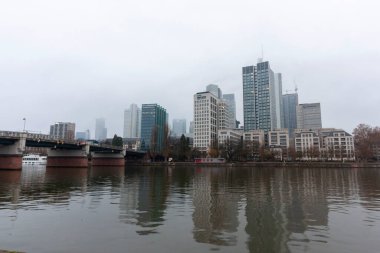 FRANKFURT (MAIN), GERMANY - 1 Aralık 2024: Frankfurt am Main River ve Bankenviertel 'in gökdelenleri bulutlu bir günde
