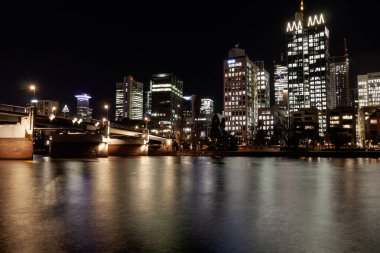 FRANKFURT (MAIN), GERMANY - DECEMBER 3, 2024: A night view of the Frankfurt am Main skyline, featuring the Main River reflecting the lights of the modern skyscrapers in the Bankenviertel and a bridge in the foreground clipart