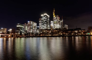 FRANKFURT (MAIN), GERMANY - DECEMBER 3, 2024: A night panoramic view of the Frankfurt am Main skyline, featuring the Main River reflecting the bright lights of the modern skyscrapers in the Bankenviertel clipart