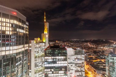 FRANKFURT (MAIN), GERMANY - DECEMBER 3, 2024: A night view from the observation deck of the Main Tower in Frankfurt am Main, Germany, showcasing close-up views of illuminated skyscrapers, including the Sparkassen-Finanzzentrum and the Main Tower itse clipart