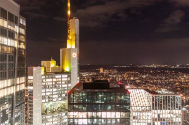 FRANKFURT (MAIN), GERMANY - DECEMBER 3, 2024: A night view from the observation deck of the Main Tower in Frankfurt am Main, Germany, showcasing close-up views of illuminated skyscrapers, including the Sparkassen-Finanzzentrum and the Main Tower itse clipart