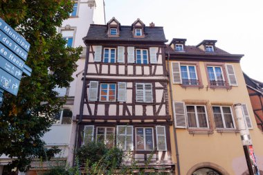 COLMAR, FRANCE - 20 EYLÜL 2024: Geleneksel Alsas mimarisi, yarı ahşap, boyalı cepheleri ve çiçeklerle dolu çiçek kutularıyla