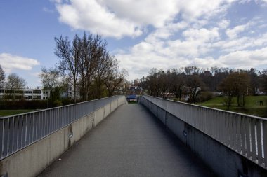 Çerçeve boyunca uzanan düz, beton bir köprü simetrik bir perspektif sunuyor.