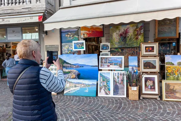 SALO, İTALYA - 22 EKİM 2024: Sanat atölyesi mağazasının önünde sayısız resim ve resim sergiliyor
