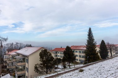 İsviçre 'nin St. Gallen kentindeki bir yamaçta karla kaplı çatıları ve balkonları olan yerleşim yerleri.