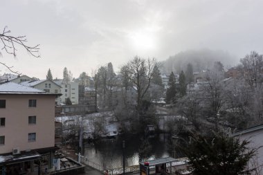 St. Gallen, İsviçre 'de kış manzarasının geniş kapsamlı panoramik manzarası, yumuşak, puslu bir gökyüzü altında kentsel gelişim ve doğal güzelliğin bir karışımını sergiliyor.