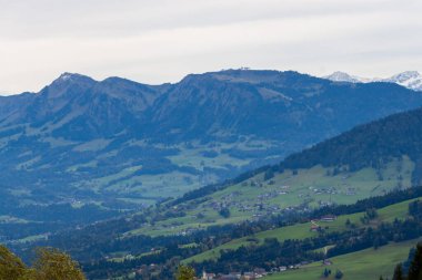 Avusturya 'daki Pfaender dağından nefes kesen panoramik manzara ufuk boyunca uzanan görkemli kar örtülü Alpleri gösteriyor.