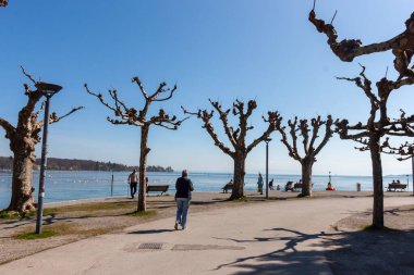 KONSTANZ, GERMANY - 5 Nisan 2025: Constance Gölü kıyıları boyunca sakin bir gezinti alanı (Bodensee) açık mavi gökyüzü altında sakin gezintileri davet eder