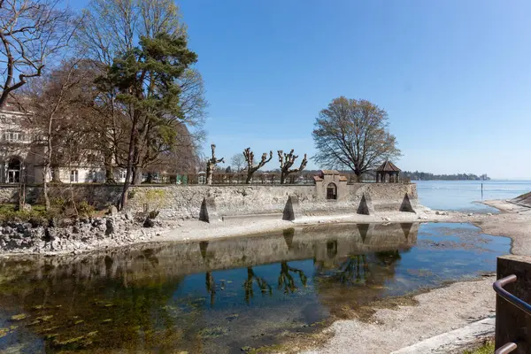 Constance Gölü (Bodensee) kıyıları boyunca sakin bir manzara, su seviyesinin düşük olması nedeniyle göl yatağının bir kısmını açığa çıkaran, su hattı boyunca kıvrımlı tarihi bir taş ihtiva etmektedir.